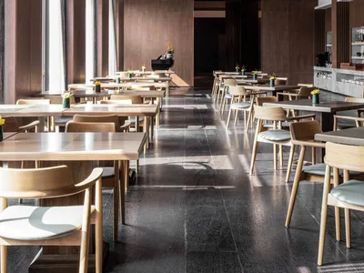 Modern restaurant interior with wooden tables, chairs, and marble accents.