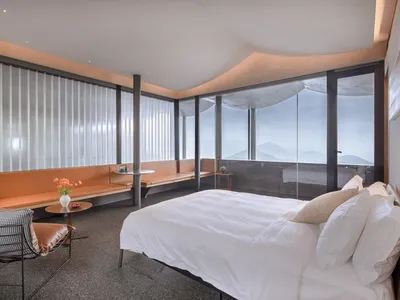 Modern minimalist bedroom featuring a white bed on a textured flooring