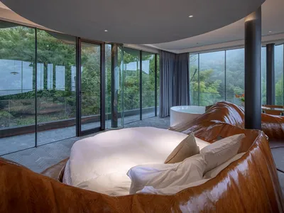 Modern bedroom interior with glass walls and a round bed.