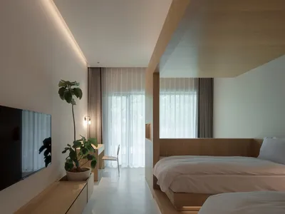 Modern bedroom featuring minimalist design with wooden furniture and white bedding.