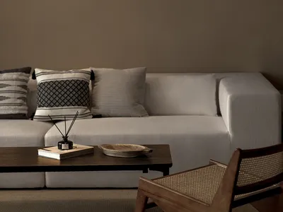 Industrial-style living room featuring a beige sectional sofa with fabric cushions, a wooden coffee table with a book and bow