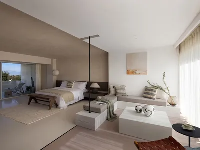 A minimalist bedroom with a white bed, neutral-colored walls, and modern furniture.