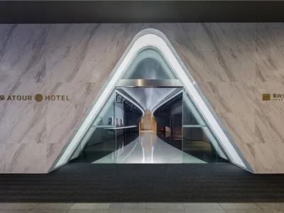 Modern hotel entrance featuring marble walls, glass doors, and metallic accents.