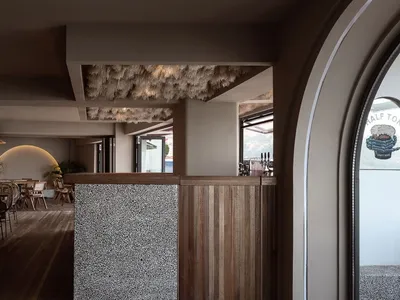 現代餐廳室內空間，搭配木製餐桌椅、石材牆面，融合當代與鄉村風格