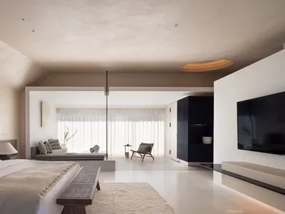 Modern minimalist bedroom with neutral materials, featuring a large bed, a sofa, and a TV.