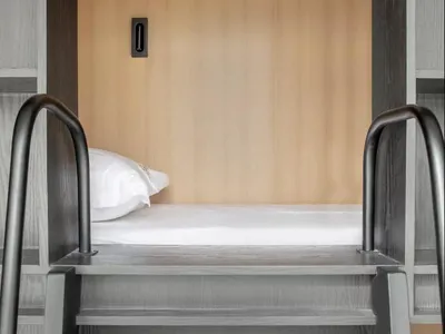 Modern minimalist bedroom featuring a wooden platform bed with a single white pillow.