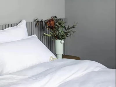 簡約臥室內擺放白色床鋪，並懸掛球形燈具。