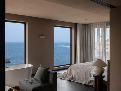 Modern minimalist bedroom with concrete floor, glass windows, and textiles