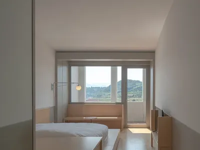 現代臥室以木質床架與長凳為主，透過大窗可眺望山景。