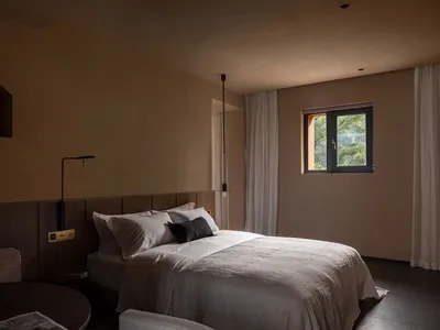 a modern minimalist bedroom with neutral color fabrics and leather furniture, featuring a large window, a simple bed with whi