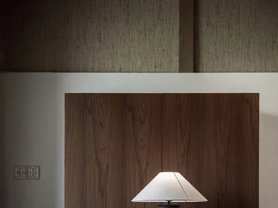 A modern home office with a wooden desk, chair, and lamp.