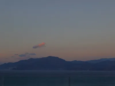 玻璃餐桌與餐椅置於餐廳空間，窗外可見夕陽與山景。