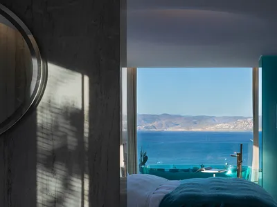 A stylish hotel room with a modern marble design, featuring a view of the ocean.