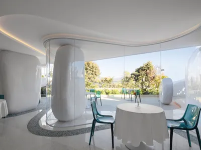 A modern restaurant interior with white tables and green chairs.