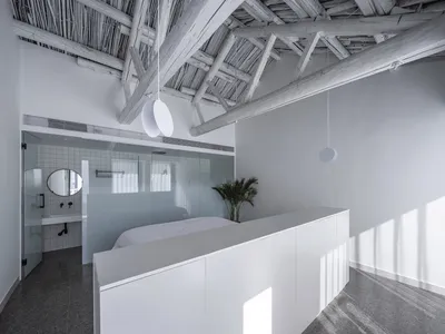 Modern minimalist bedroom featuring concrete floor and wooden ceiling beams.