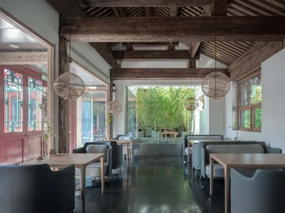 Modern restaurant interior with concrete flooring and bamboo plants.