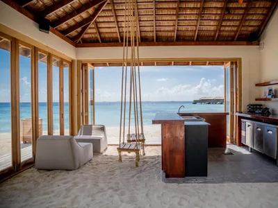 Minimalist residential kitchen with wooden finishes and a view of the ocean.