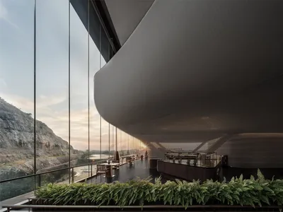 A modern restaurant features a glass ceiling and large terrace overlooking a landscape.