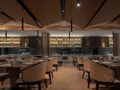 Modern industrial restaurant interior with wooden tables, concrete walls, and metal accents.