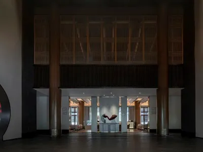 現代酒店大廳，設有混凝土柱與地板，中央擺放大型雕塑。