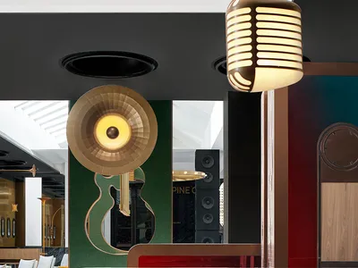 A modern hotel reception counter with a brass and leather finish, featuring a retro microphone light fixture and a guitar-sha