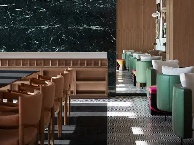 Modern restaurant interior featuring a marble wall and wooden tables.