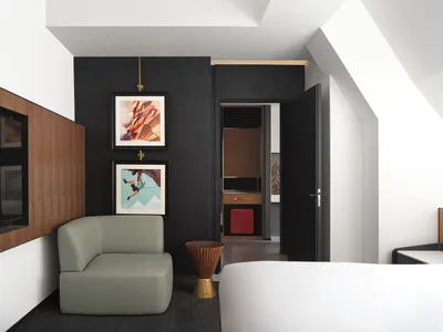 Modern hotel room with black accent wall, minimalist decor, and a green lounge chair.