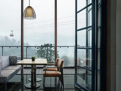 Modern metallic restaurant interior with bar seating, large windows, and mountain view.