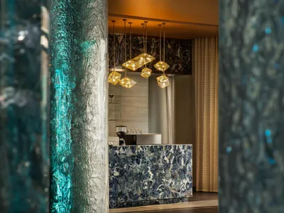 Modern hotel lobby with marble finishes and glass pendant lights.
