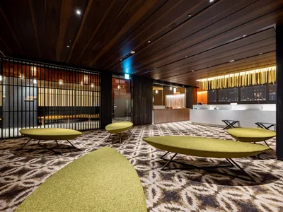 A modern hotel lobby with textured carpets and wooden paneling.