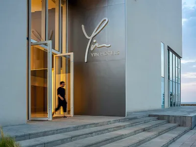 A modern, minimalist hotel entrance with a concrete facade and a sign reading 'YIN HOTELS'.