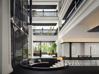 Modern hotel lobby with black glass accents, black glass railings, and stone columns.