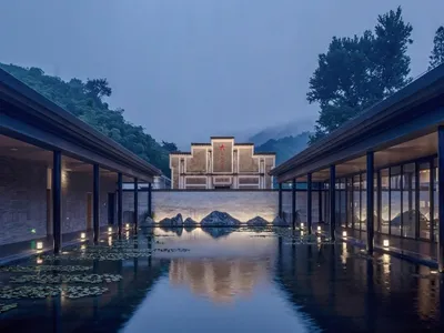 A modern hotel lobby with a water feature, glass walls, and stone walls.