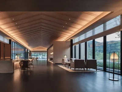 Modern hotel lobby with wood paneling, glass windows, and concrete flooring