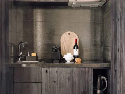 A modern, minimalist residential kitchen featuring wooden cabinets and a concrete countertop.