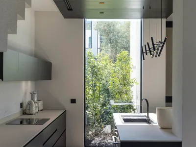 Modern minimalist kitchen with sleek black cabinetry and a large window overlooking greenery.
