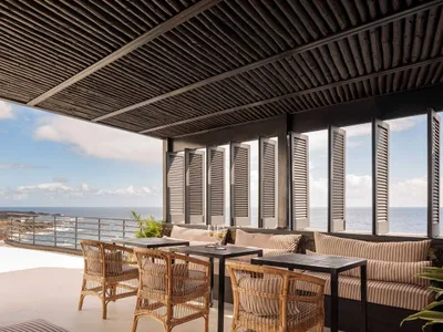 Modern restaurant interior with wooden tables, chairs, and ceiling.