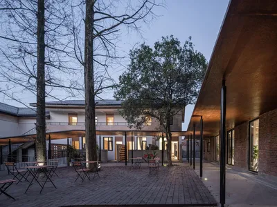 Outdoor seating area of a modern restaurant with copper walls and wooden flooring.
