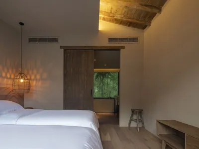 Bedroom with minimalist decor, featuring a wooden bed and a wicker pendant lamp.