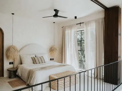 A minimalist bedroom with a bed, curtains, and a ceiling fan.