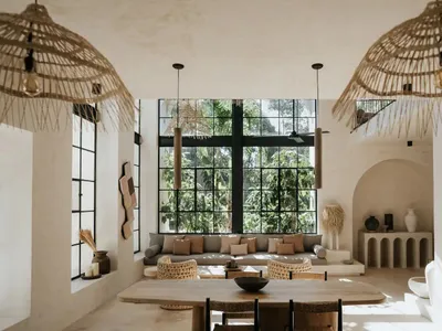 A minimalist living room with concrete walls, a large window, and rattan pendant lights.