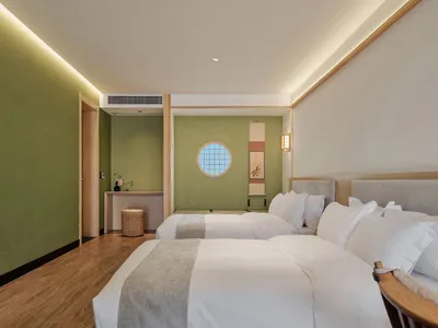 Well-lit bedroom with minimalist decor featuring wooden floors and beige textiles.