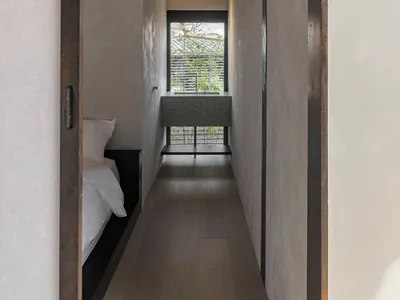 現代臥室，設有天花板木樑、白床，以及窗外綠意景觀。