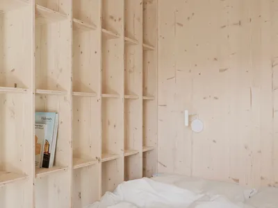 A minimalist bedroom with wooden walls and shelves.