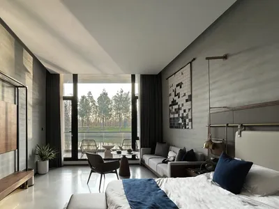 A minimalistic bedroom featuring contemporary furniture, a large window overlooking trees, and a cozy seating area with a sof