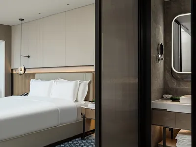 A modern minimalist bedroom featuring neutral tones and clean lines, showcasing a comfortable yet stylish space.