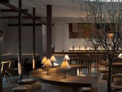 A stylish restaurant bar with a wooden bar counter and pendant lights.