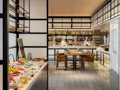 Modern restaurant interior with chefs preparing food behind a buffet counter.