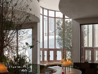 Interior of a modern restaurant featuring wooden tables, concrete benches, and contemporary design elements.