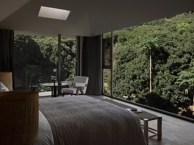 Modern bedroom featuring a glass window border with a view of lush greenery.